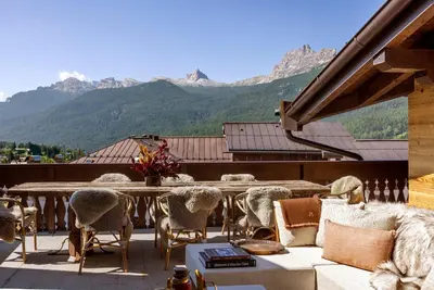 a patio with a table and chairs and mountains at Ancora Cortina - The Leading Hotels of the World in Cortina dʼAmpezzo