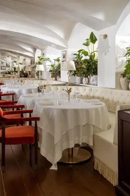 a restaurant with white tables and chairs and plants at Ancora Cortina - The Leading Hotels of the World in Cortina dʼAmpezzo