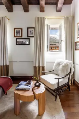 a living room with a chair and a table and a window at Ancora Cortina - The Leading Hotels of the World in Cortina dʼAmpezzo