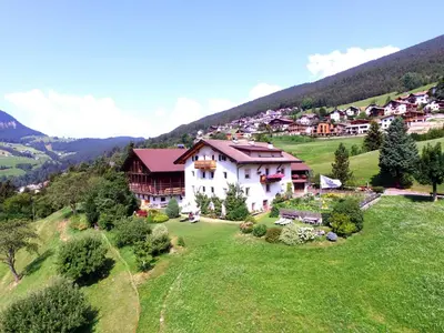 a large white house on a green hillside at Sule Hof Agriturismo in Ortisei