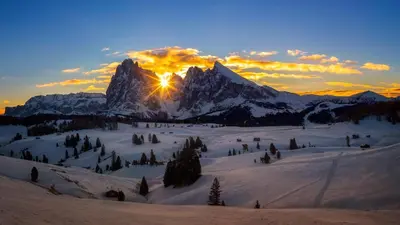 a snow covered mountain with the sun setting behind it at Sule Hof Agriturismo in Ortisei