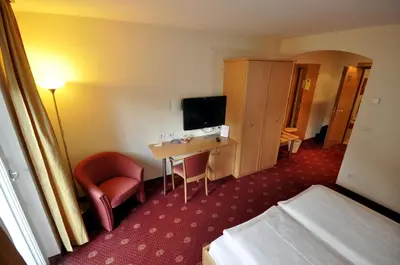a hotel room with a desk and a bed and a television at Cityhotel Tallero in Bressanone