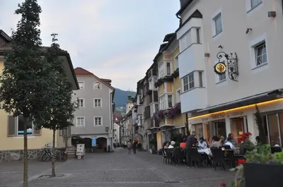 a street in a town with people sitting at tables at Cityhotel Tallero in Bressanone