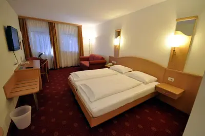 a hotel room with a bed and a chair at Cityhotel Tallero in Bressanone