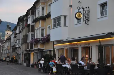 a group of people sitting at tables outside a building at Cityhotel Tallero in Bressanone