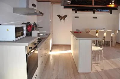 a kitchen with white cabinets and a counter with a microwave at Meraviglioso Loft con vista sulle Dolomiti in Colle Santa Lucia
