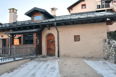 a house with a front door with snow on the ground at Meraviglioso Loft con vista sulle Dolomiti in Colle Santa Lucia