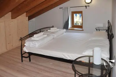 a bed with white sheets and a glass table at Meraviglioso Loft con vista sulle Dolomiti in Colle Santa Lucia