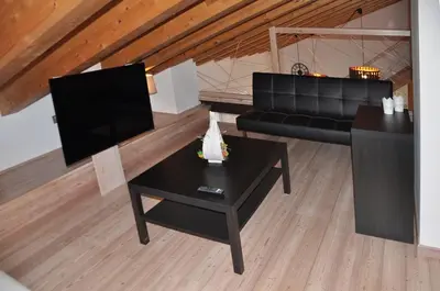 a living room with a black couch and a table at Meraviglioso Loft con vista sulle Dolomiti in Colle Santa Lucia
