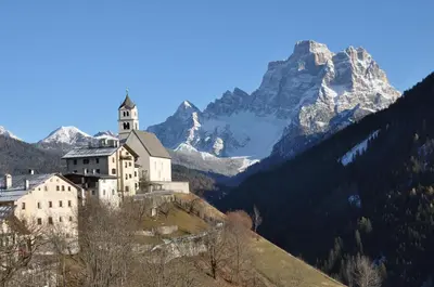 a castle on a hill with a mountain in the background at Meraviglioso Loft con vista sulle Dolomiti in Colle Santa Lucia