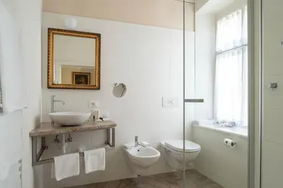 a bathroom with a sink and a toilet and a mirror at Villa Bergmann Suites Meran in Merano