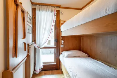 a bedroom with two bunk beds and a window at Cozy 3 bedroom with access to garden in Cortina dʼAmpezzo