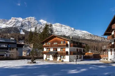 a building with snow covered mountains in the background at Chalet Stadio in Cortina dʼAmpezzo