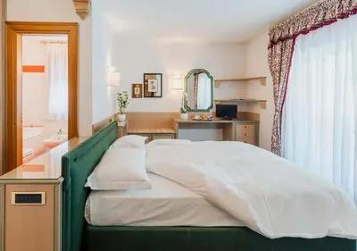 a bedroom with a bed and a desk and a mirror at Chalet Stadio in Cortina dʼAmpezzo
