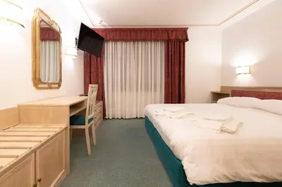 a hotel room with two beds and a desk at Chalet Stadio in Cortina dʼAmpezzo