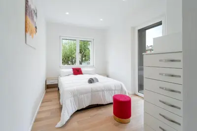a white bedroom with a bed and a window at Villa Silvio in Castello di Fiemme