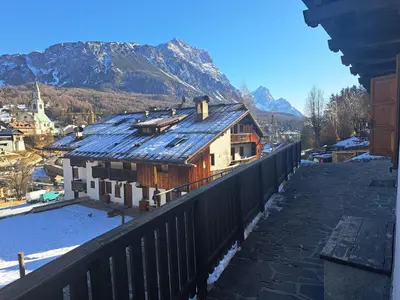 a house on a balcony with a mountain in the background at Comodo e luminoso, splendida vista su Cortina in Cortina dʼAmpezzo