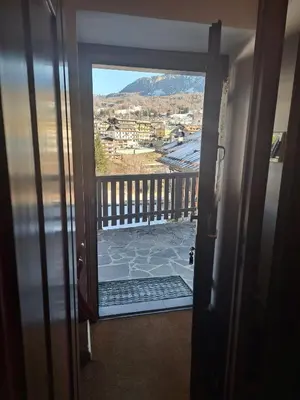 a door to a balcony with a view of a city at Comodo e luminoso, splendida vista su Cortina in Cortina dʼAmpezzo