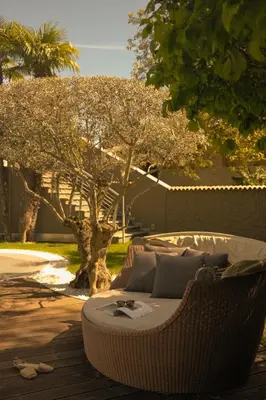 a wicker couch sitting on a patio in front of a tree at Hotel Mühlbacherhof in Lagundo