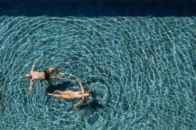 two people swimming in a pool of water at Tirolensis - Luxury All Inclusive in Tesimo
