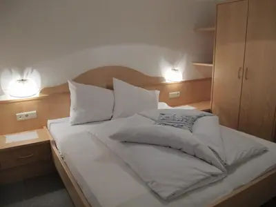 a bedroom with a bed with white sheets and pillows at Residence Adler in Tesimo