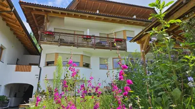 a building with a balcony and flowers in front of it at Pension Pepi - Apartments I Bed - Breakfast in Perca