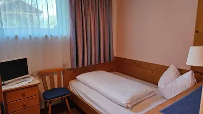 a small bedroom with a bed and a desk with a computer at Pension Pepi - Apartments I Bed - Breakfast in Perca