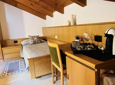 a bedroom with a bed and a desk with a desk at Stanza Roma in Tesero