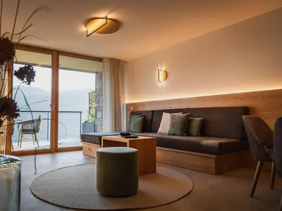 a living room with a couch and a large window at Gruberhof Lana - NEW! in Lana