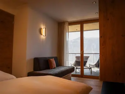 a hotel room with a bed and a chair and a window at Gruberhof Lana - NEW! in Lana