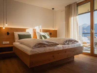 a bedroom with a wooden bed with a large window at Gruberhof Lana - NEW! in Lana
