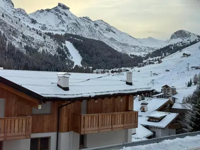 a snow covered roof of a building with mountains in the background at Ciasa Enrico in Arabba