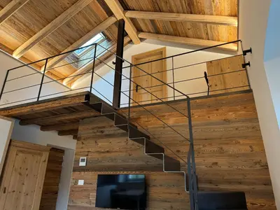 a staircase in a house with wooden ceilings and a tv at Alpen Chic in Cavalese