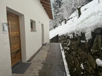 a walkway next to a stone wall with snow on it at Alpen Chic in Cavalese