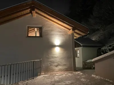 a light on the side of a building at night at Alpen Chic in Cavalese