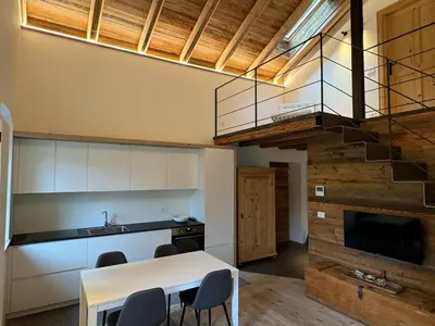 a kitchen with a table and chairs and a staircase at Alpen Chic in Cavalese