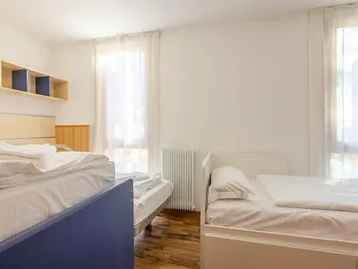 a white bedroom with two beds and a window at Apartment Condominio Val di Fassa-3 by Interhome in Alba di Canazei