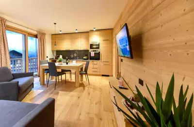 a living room with a table and a tv on a wall at Apartments Alla Caminada in Alleghe