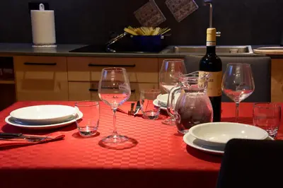 a table with glasses and plates and a bottle of wine at Apartments Alla Caminada in Alleghe