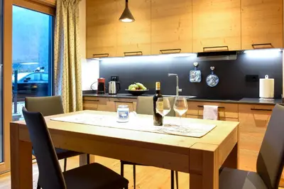 a kitchen with a wooden table with wine glasses at Apartments Alla Caminada in Alleghe