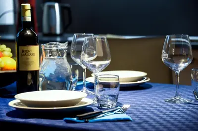 a table with glasses and plates and a bottle of wine at Apartments Alla Caminada in Alleghe