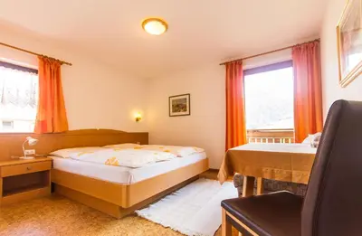 a bedroom with a bed and a desk and windows at Apartements Mitterstill in Fiè