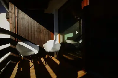 a room with two white chairs and a wall at A93A Apartment Alicia in Carano