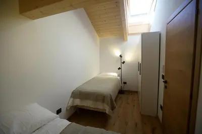 a white bedroom with two beds and a window at A93A Apartment Alicia in Carano