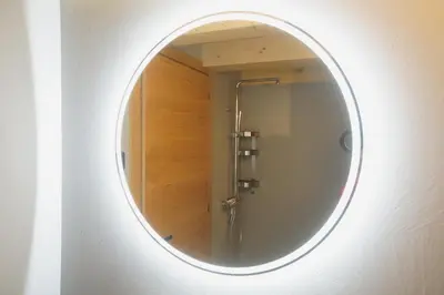 a round mirror on a wall with a shower at A93A Apartment Alicia in Carano