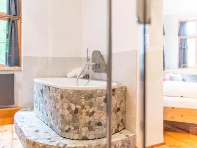 a bathroom with a stone tub with a sink at Apartments Ansitz Wildberg in San Lorenzo di Sebato