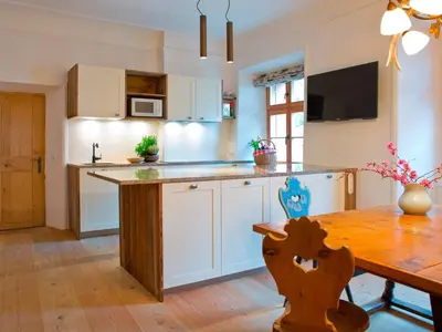 a kitchen with white cabinets and a wooden table at Apartments Ansitz Wildberg in San Lorenzo di Sebato