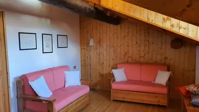 two pink chairs in a room with wooden walls at Dolomites Holiday Home in Rivamonte