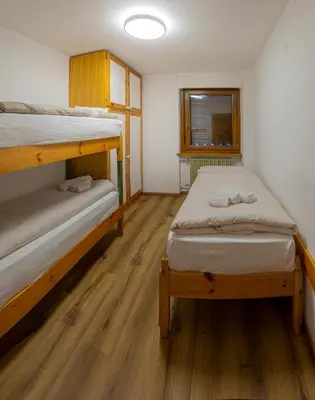 two bunk beds in a room with wooden floors at Appartamento Martino in San Martino di Castrozza