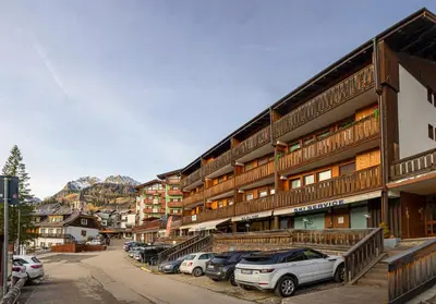 a building with cars parked in a parking lot at Appartamento Martino in San Martino di Castrozza